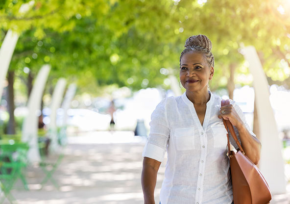 Adult woman walking through a park with her purse